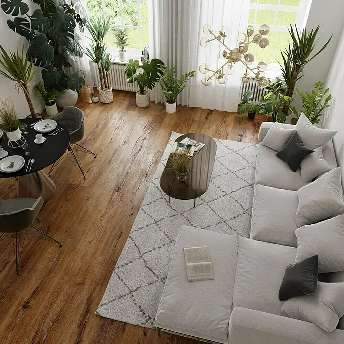 Parkett - Eiche Antik Laax, Landhausdiele, 1.900 x 190 x 15 mm - Eine moderne Wohnzimmerszene mit einem grauen Ecksofa, einem ovalen Couchtisch und einem Esstisch mit Stühlen, umgeben von Zimmerpflanzen.