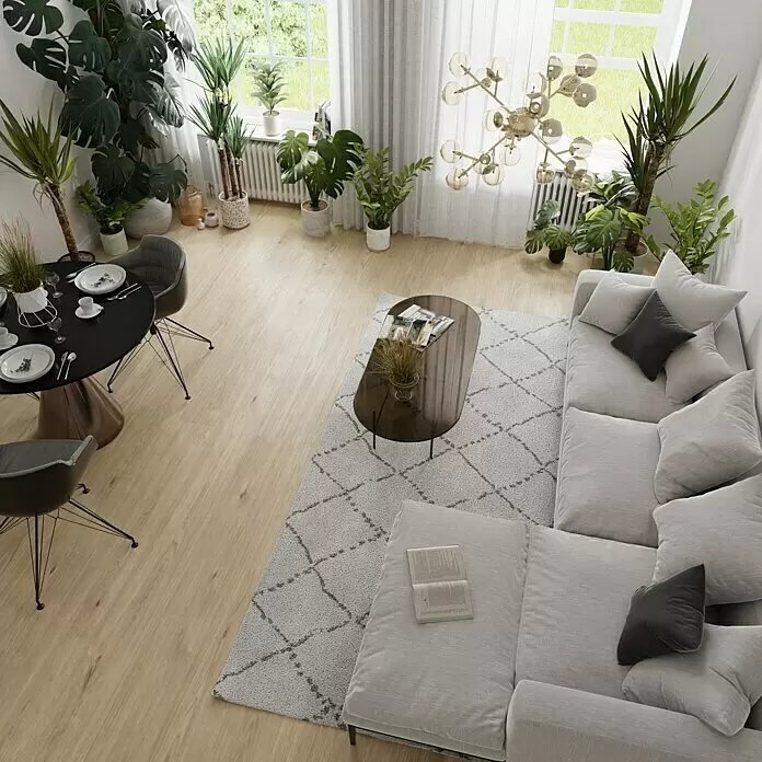 Parkett - Eiche Innsbruck, Landhausdiele, 2.200 x 260 x 15 mm - Ein offener Wohnbereich mit einem hellgrauen Ecksofa, Couchtisch und einem schwarzen Esstisch, umgeben von zahlreichen Grünpflanzen.
