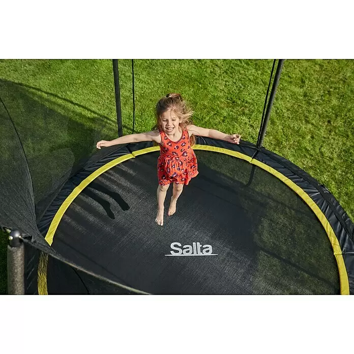 Salta Trampolin Comfort Edition - Durchmesser: 153 cm, Schwarz - Ein fröhliches Mädchen springt hoch auf einem schwarzen Trampolin mit leuchtend gelbem Rand und Sicherheitsnetz.