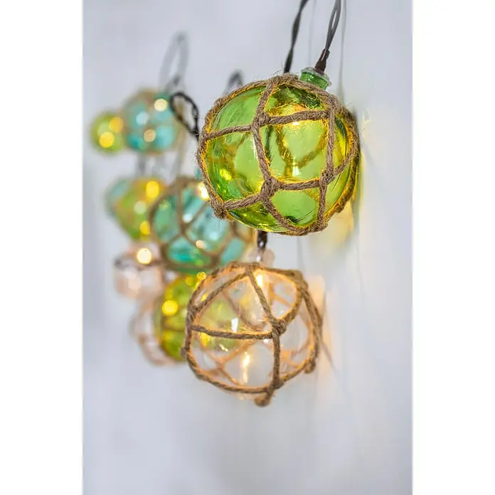 New Garden Guirnalda decorativa Mare - 10 W, L x An x Al: 3,3 m x 6 cm x 6 cm, Multicolor - Primer plano de una serie de luces con boyas decorativas de vidrio de colores, envueltas en una rústica red de cuerda, que emiten un cálido resplandor.