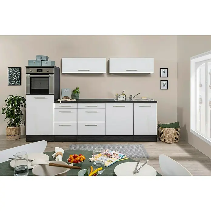 Respekta Premium Cocina de isla Amanda - Ancho: 280 cm, Roble/Blanco, Con electrodomésticos - Vista de cocina con armarios blancos, cajones y horno empotrado, complementado con una encimera oscura y decoraciones.