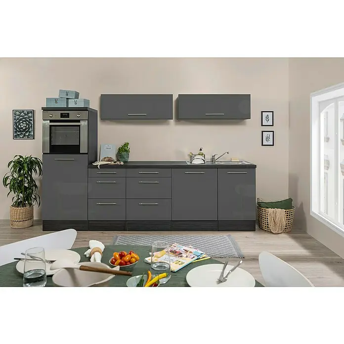 Respekta Premium Cocina de isla Amanda - Ancho: 280 cm, Roble/Gris, Con electrodomésticos - Escena de cocina con armarios grises, horno empotrado y decoración. Se puede ver una mesa puesta en primer plano.