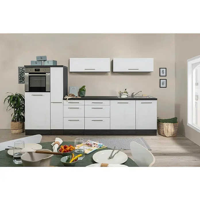 Respekta Premium Cocina de isla Amanda - Ancho: 310 cm, Roble/Blanco, Con electrodomésticos - Cocina luminosa con armarios blancos, encimeras oscuras y horno integrado. Acogedora zona de comedor con una mesa puesta en primer plano.