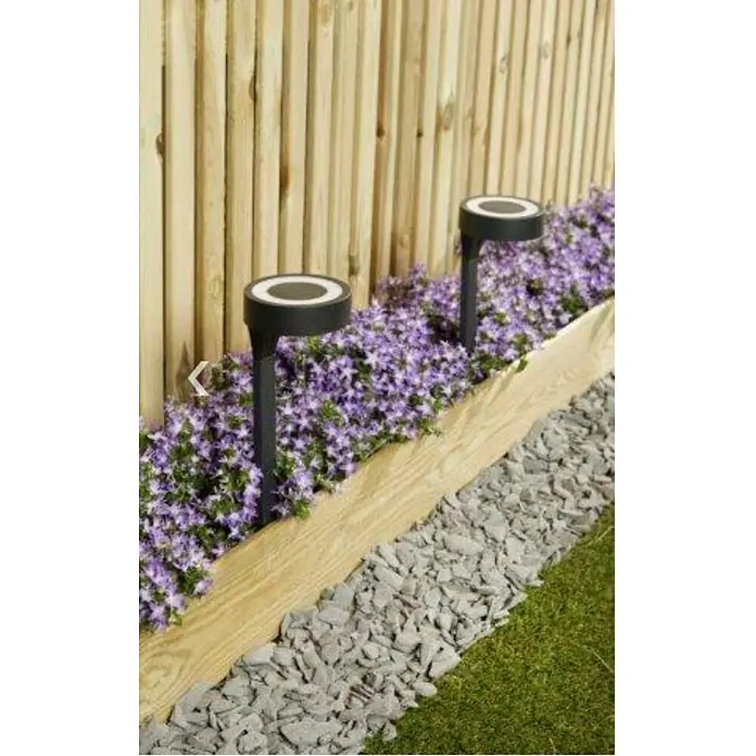 Estaca solar Orange - L x An x Al: 11 x 11 x 40 cm, Negro, IP33, 10 lm - Vista del jardín con dos luces solares colocadas entre flores púrpuras y una cerca de madera, creando un ambiente acogedor.
