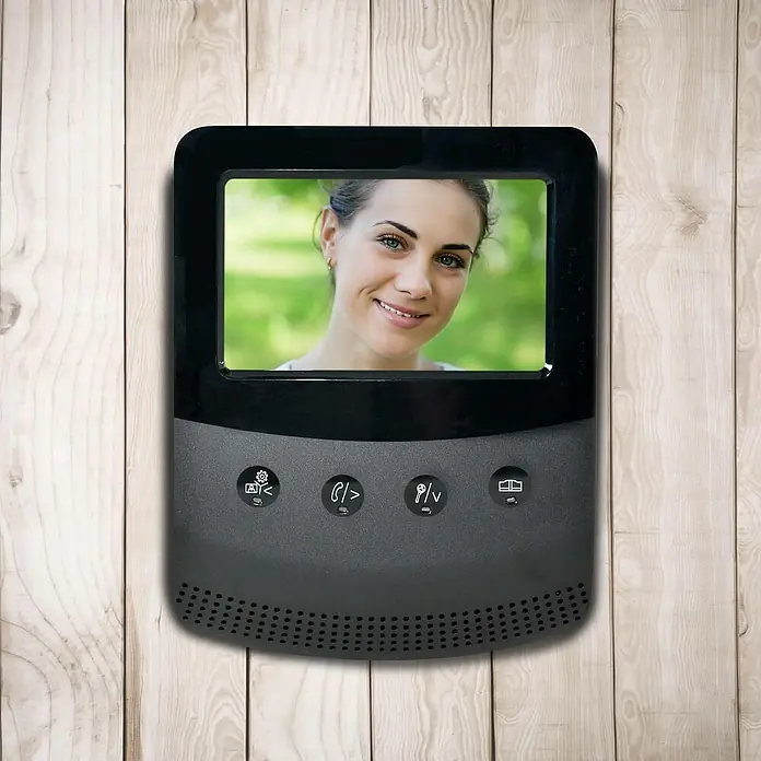 Avidsen Interfono con pantalla LCD - L x An x Al: 3,5 x 7 x 16,5 cm - Primer plano de un timbre moderno con una pantalla que muestra la cara de una mujer, montado en una pared de madera.