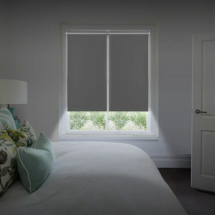 Estor enrollable opaco Clip&Fix Blackout Reflect - An x Al: 90 x 180 cm, Plata - Dos persianas enrollables dobles grises oscurecen la ventana de un dormitorio, pero la luz suave del día hace que la habitación parezca acogedora.