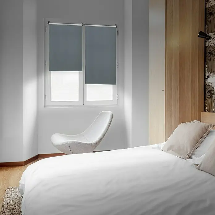 Estor enrollable opaco Clip&Fix Blackout Reflect - An x Al: 90 x 180 cm, Plata - Un dormitorio con elegantes estores grises instalados en una ventana, creando un ambiente tranquilo y relajante en el interior.