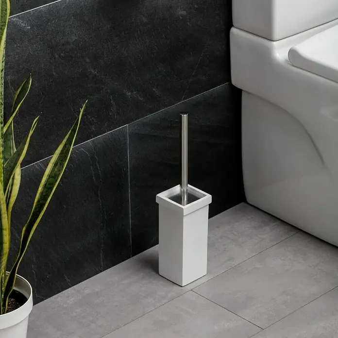 Tatay Iconik Escobillero de suelo - Acero inoxidable, Cromo/Blanco - Un escobillero blanco con mango de acero inoxidable colocado sobre un piso de baldosas grises en un baño con paredes de azulejos oscuros.