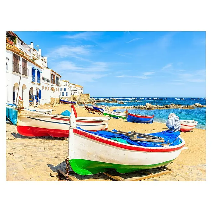 Cuadro Gerona - Playa Calella Palafrugell, 80 x 60 cm - Pintoresca escena costera con barcos de pesca coloridos en la playa y edificios blancos bajo un cielo azul brillante.