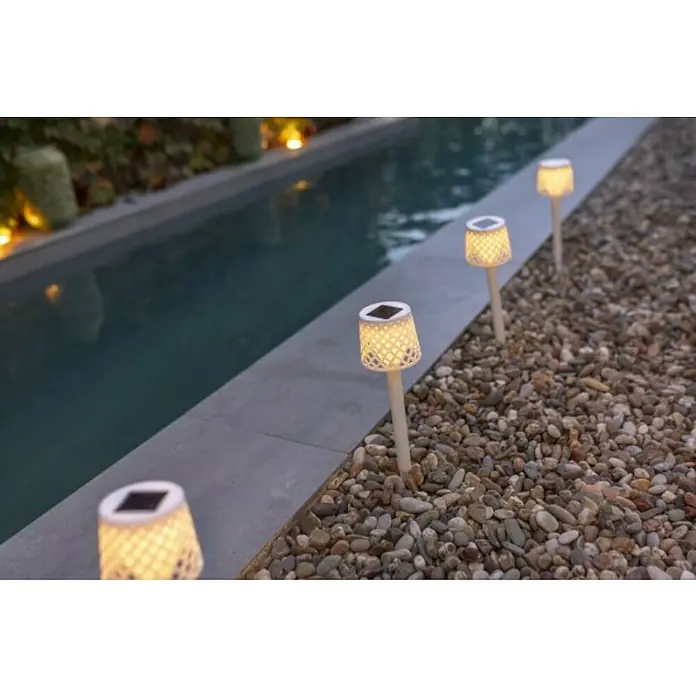 New Garden Lámpara solar Gretita - 0,5 W, Ø x Al: 9 x 39 cm, Blanco, 4 ud. - Primer plano de luces solares que bordean un sendero de jardín, emitiendo un brillo cálido. Luces decorativas para exteriores.