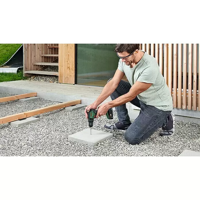 Bosch Power for All 18V Akku-Schlagbohrschrauber UniversalImpact 18V-60 - 18 V, 2 Akkus, 2 Ah, 60 Nm - Mann bohrt mit einer grün-schwarzen Bosch Akku-Bohrmaschine ein Loch in eine Betonplatte.