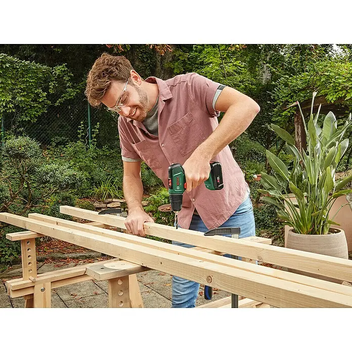 Bosch Power for All 18V Akku-Bohrschrauber EasyDrill 18V-40 - 18 V, 2 Akkus, 2 Ah, 40 Nm - Ein Mann bohrt mit einem Bosch Akku-Bohrschrauber ein Holzbrett. Die Bohrmaschine ist gut sichtbar und im Fokus des Bildes.