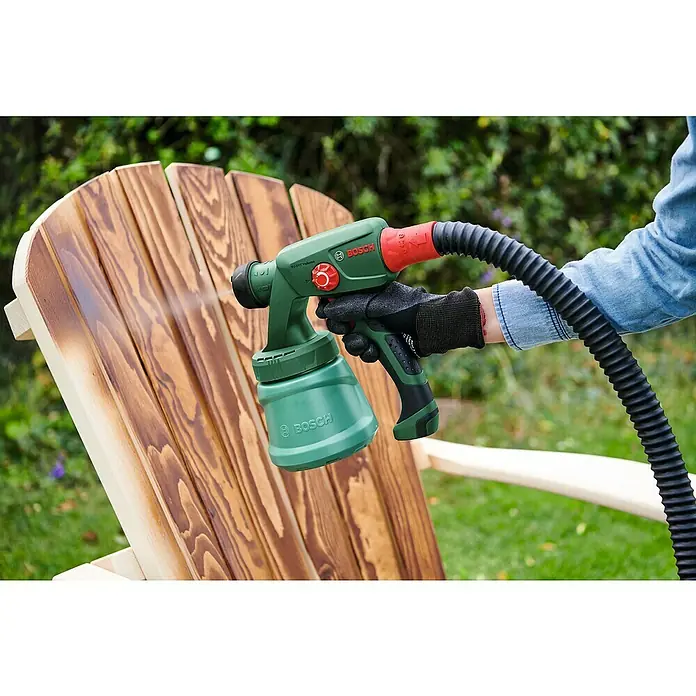 Bosch Power for All 18V Akku-Farbsprühsystem EasySpray 18V-100 - 18 V, Ohne Akku, Max. Fördermenge: 0,1 l/min - Eine Person sprüht mit einer Bosch Farbspritzpistole Farbe auf einen Holzstuhl, um ihm ein neues Aussehen zu verleihen.