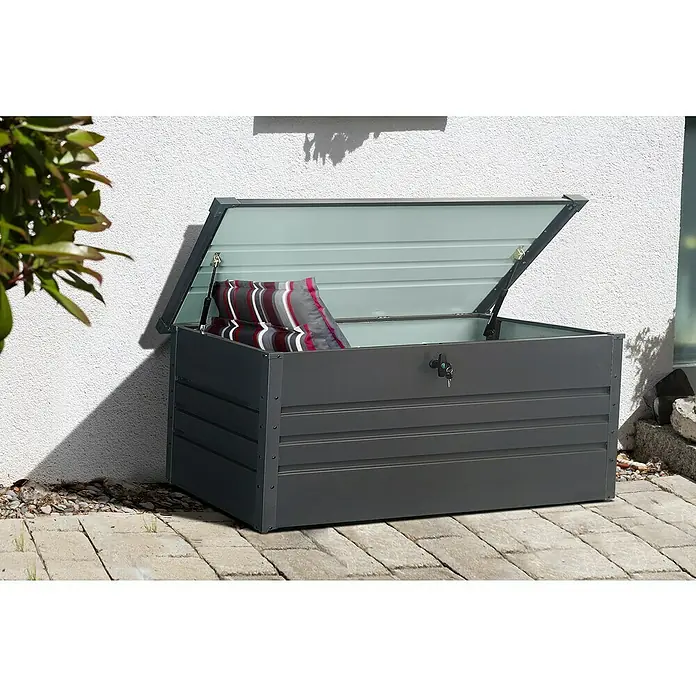 Gardol Garten-Aufbewahrungsbox - L x B x H: 165 x 70 x 62 cm, Anthrazit, Metall - Diese Aufnahme zeigt eine graue Gartenbox mit geöffnetem Deckel, in der sich ein Kissen befindet. Die Gartenbox steht auf einem gepflasterten Untergrund.