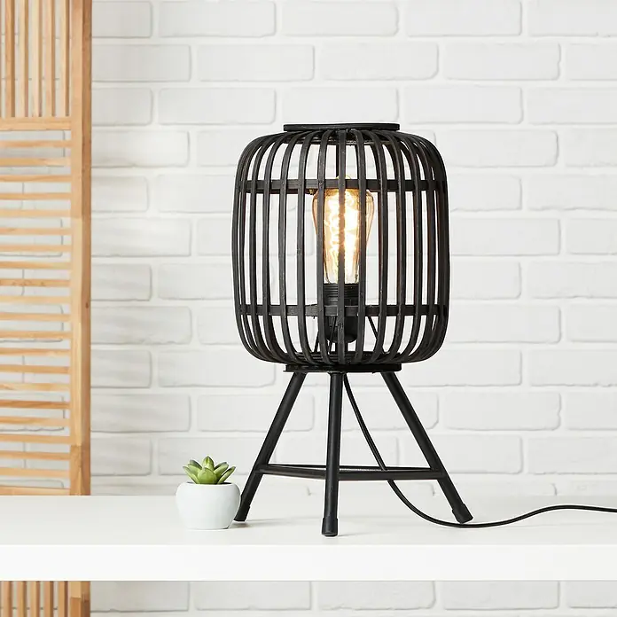Brilliant Woodrow Tischleuchte - Schwarz, E27, 60 W - Schwarze Käfig-Tischleuchte mit Stativfuß und warm leuchtender Glühbirne als stimmungsvolle Beleuchtung auf einem Tisch.