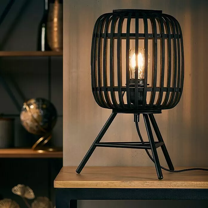Brilliant Woodrow Tischleuchte - Schwarz, E27, 60 W - Schwarze Tischlampe aus Holzlamellen und Metall mit warmer Glühbirne, auf einer Holzoberfläche.
