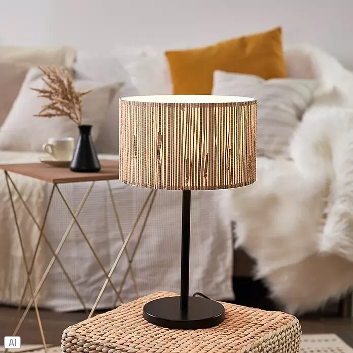 Brilliant Wimea Tischleuchte - 52 W, Schwarz, E27 - Tischlampe mit schwarzem Fuß und natürlichem Weblampenschirm, warmes Licht spendend. Sie steht auf einem Flechthocker neben einem Sofa.