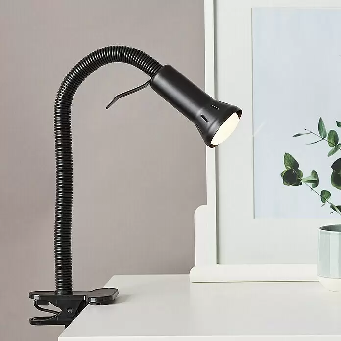 Brilliant Klemmleuchte Flex - 40 W, Farbe Gehäuse: Schwarz - Schwarze Klemmlampe mit flexiblem Schwanenhals, leuchtend, an weißer Oberfläche befestigt.