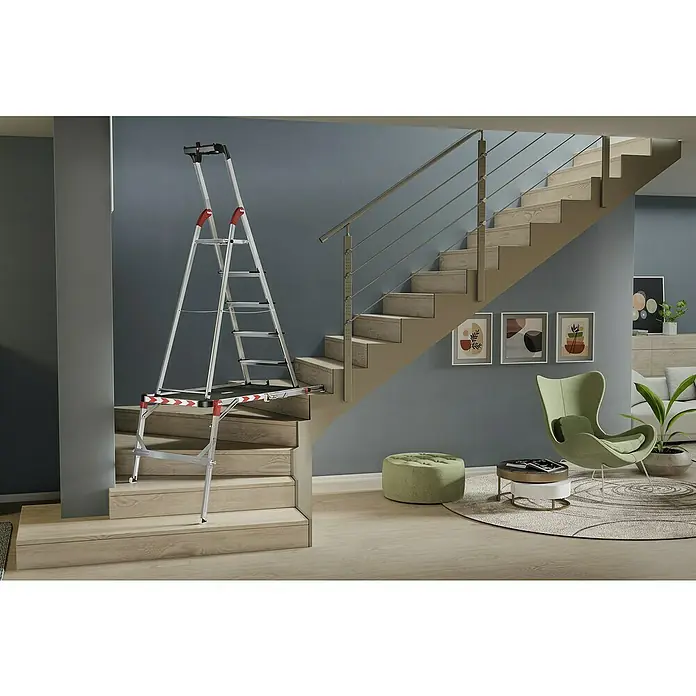 Hailo Treppenpodest TP Plus - Belastbarkeit: 160 kg, Aluminium - Eine silberne, mehrstufige Treppenleiter mit roter Markierung steht auf einer Holztreppe in einem Haus.