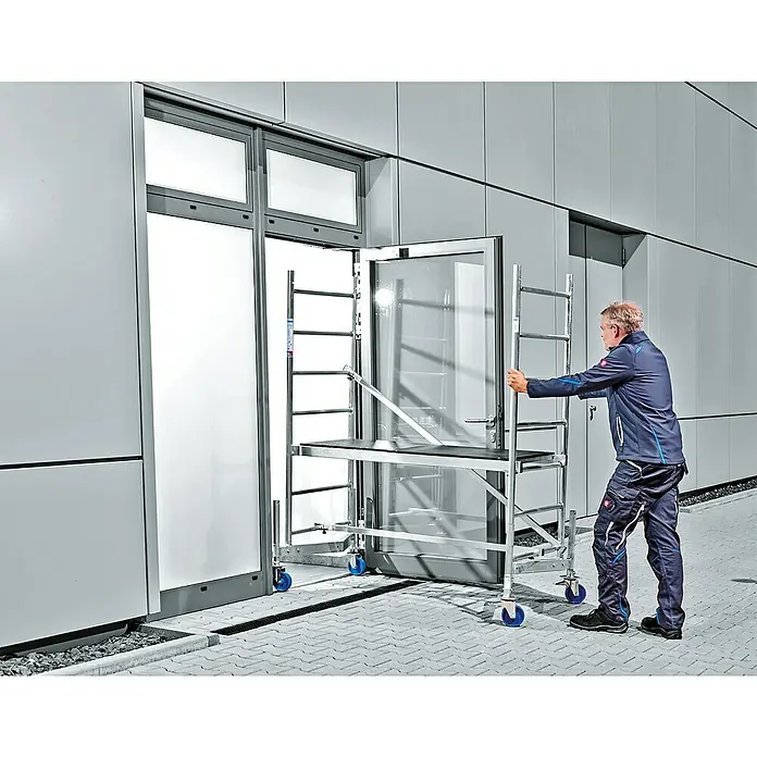 Krause ClimTec Rollgerüst - Arbeitshöhe: 3 m - Ein Mann schiebt ein fahrbares Gerüst mit blauen Rollen durch eine Tür. Das Gerüst hat eine Arbeitsplattform und Leiter.