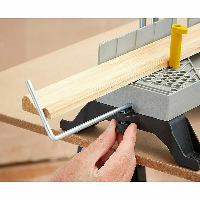 Stanley Gehrungslade 1-20-800 mit Säge - L x B x H: 560 x 143 x 95 mm - Eine Gehrungslade mit einem Holzstück, das von einer Hand an der Schraube gehalten wird. Perfekt für präzise Holzarbeiten.