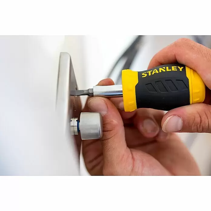 Stanley Vergaser Schraubendreher Stubby 0-66-357 - 8 -tlg. - Eine Hand hält einen gelb-schwarzen Stanley Schraubendreher und dreht damit eine silberne Vorrichtung.