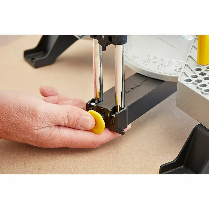 Stanley Gehrungslade 1-20-800 mit Säge - L x B x H: 560 x 143 x 95 mm - Detailansicht einer Gehrungssäge mit Hand, die einen gelben Knopf bedient, zur präzisen Winkelanpassung beim Holzzuschnitt.