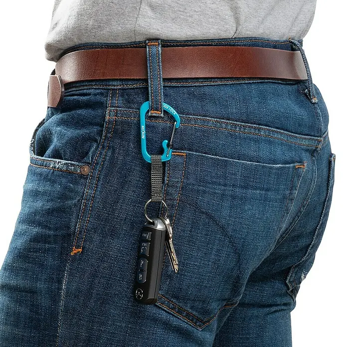 Nite Ize Karabinerhaken Slidelock Key Ring - Blau - Nahaufnahme von Jeans mit braunem Gürtel und einem blauen Karabinerhaken mit Schlüsselanhänger, der an einer Schlaufe befestigt ist.