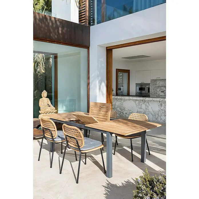 Sunfun Melina Silla de jardín - Polietileno / polipropileno, Apilable, Marrón, An x Pr x Al: 54 x 59 x 82 cm - Un moderno conjunto de comedor exterior con mesa de madera y sillas de mimbre con cojines grises, creando un ambiente elegante y cómodo.