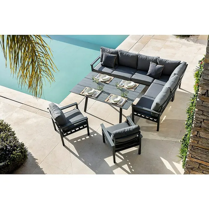 Conjunto de muebles Simona - 7 pzs., Acero/Polywood, Gris oscuro - Un moderno conjunto de sofás gris con mesa de comedor y sillas está situado al aire libre junto a una piscina. Diseño elegante para relajarse.