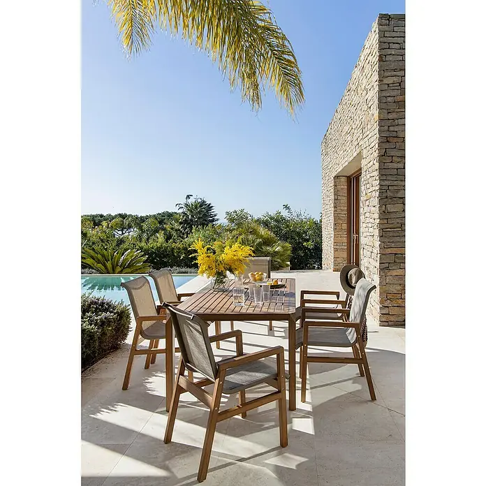 Conjunto de muebles Flavium - 7 pzs., Textiline/Enviro Imitation Wood®, Natural - Agradable escena al aire libre con una elegante mesa de comedor y sillas a juego bajo un árbol frondoso.