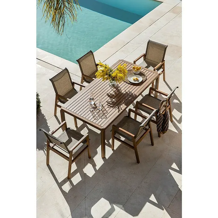 Conjunto de muebles Flavium - 7 pzs., Textiline/Enviro Imitation Wood®, Natural - Un juego de comedor exterior con seis sillas, perfecto para comidas al aire libre. El conjunto está situado en un patio junto a una piscina.