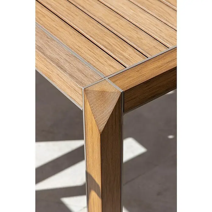 Conjunto de muebles Flavium - 7 pzs., Textiline/Enviro Imitation Wood®, Natural - Primer plano de una mesa de madera con detalles metálicos, mostrando el diseño elegante con patrones de sombra interesantes.