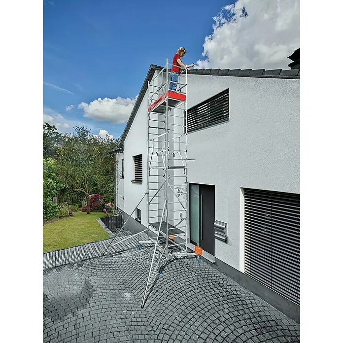 Krause ClimTec Leitergerüst - Arbeitshöhe: 7 m, Ohne Rollen - Eine Frau auf einem fahrbaren Gerüst beim Arbeiten an einem Hausdach. Das Gerüst ist aus Aluminium und hat eine rote Plattform.
