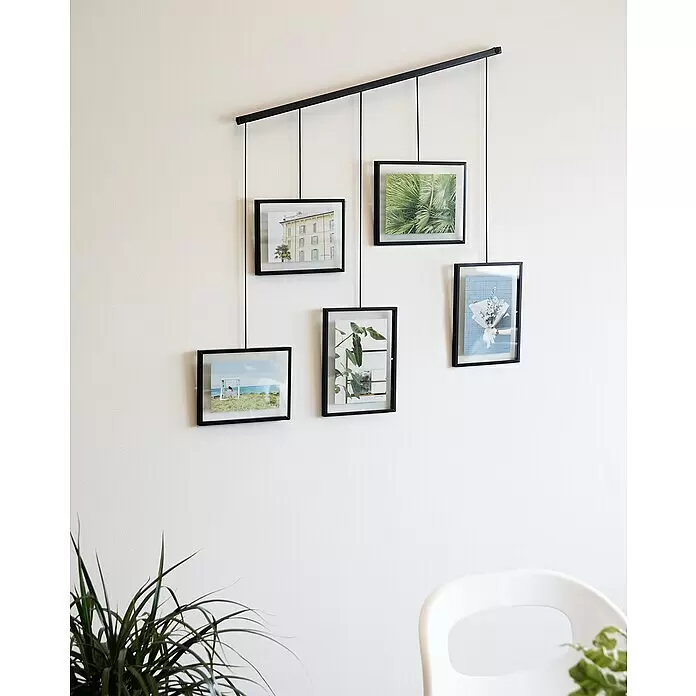 Umbra Bilderrahmen-Set Exhibit - 2 x 10x15 cm, 3 x 13x18 cm, Schwarz, Metall - Ein schwarzes wandmontiertes Fotodisplay-System mit einer horizontalen Stange, an der fünf schwarzgerahmte Bilder hängen.