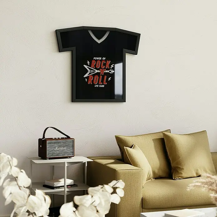 Umbra Bilderrahmen Trikot - 62 x 72 cm, Schwarz - Ein T-Shirt-förmiger Bilderrahmen mit dem Aufdruck "Power of Rock n Roll" hängt an einer Wand im Wohnzimmer, neben einem Lautsprecher.