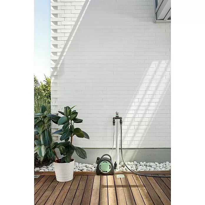 G.F. Garden Reco Schlauchbox Aquabag - Schlauchlänge: 10 m, Freistehend - Schwarze und grüne Gartenschlauchhaspel und -verteiler, an ein Rohr auf einer Holzterrasse für die Gartenbewässerung angeschlossen.