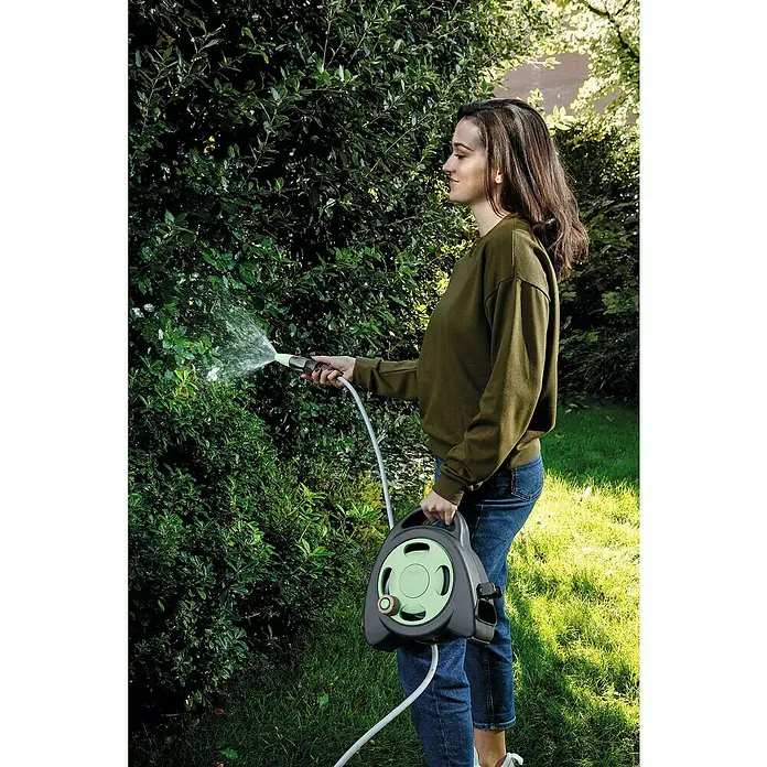 G.F. Garden Reco Schlauchbox Aquabag - Schlauchlänge: 10 m, Freistehend - Frau gießt Pflanzen mit einem grauen Schlauchaufroller mit einem grünen Detail.