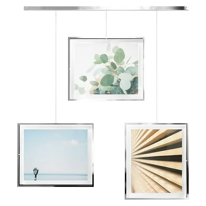 Umbra Bilderrahmen-Set Exhibit - 3 x 20x25 cm, Chrom, Metall - Diese Produktaufnahme zeigt eine schwebende Bildergalerie. Die Bilder sind mit einer eleganten, silbernen Aufhängung und Rahmen versehen.
