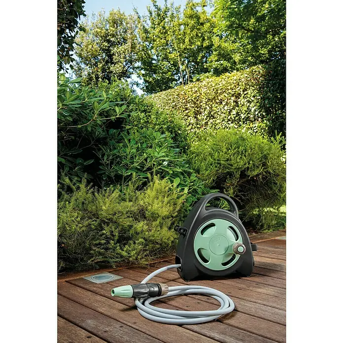 G.F. Garden Reco Schlauchbox Aquabag - Schlauchlänge: 10 m, Freistehend - Eine tragbare Gartenschlauchbox mit einem grauen Schlauch und einem grünen Anschlussstück liegt auf einer Holzterrasse vor üppigem Grün.