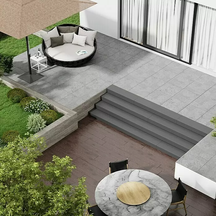 Marazzi Terrassenfliese Esterno 20T Gris Fleury - 60 x 60 x 2 cm, Grau, Matt - Moderne Außenterrasse mit beigem Sonnenschirm über einem runden Tagesbett auf grauen Fliesen, die zu einer Holzterrasse mit Marmortisch, Stühlen und Beeten führt.