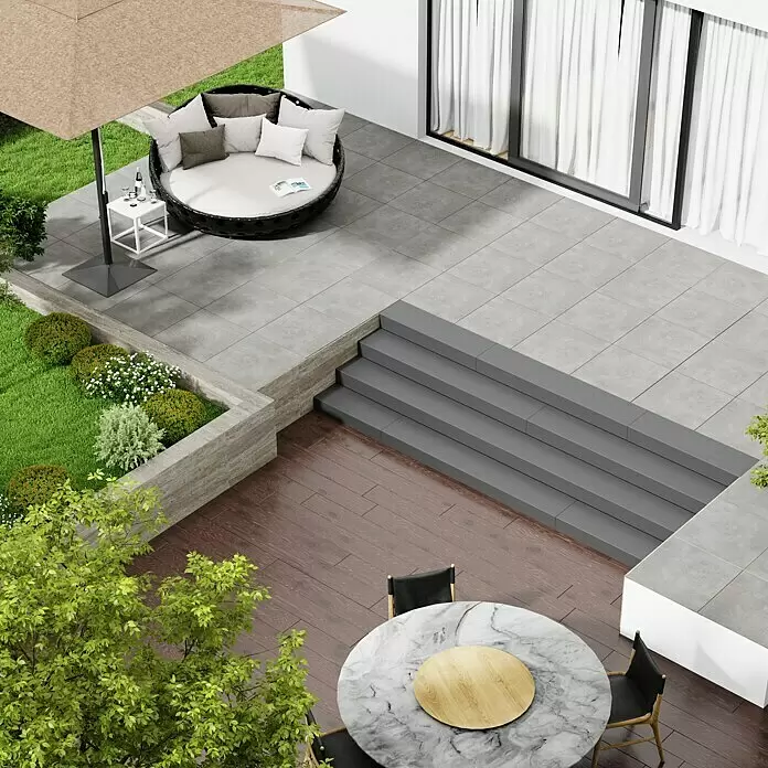 Marazzi Terrassenfliese Esterno 20T Plaster Grey - 60 x 60 x 2 cm, Grau, Matt - Außenterrasse mit einem runden Tagesbett unter einem beigefarbenen Sonnenschirm und einem Marmor-Esstisch mit schwarzen Stühlen auf Holzdeck.