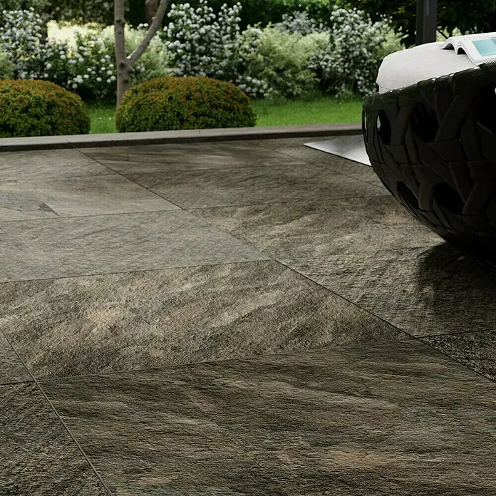 Marazzi Terrassenfliese Esterno 20T Rocking Grey - 60 x 60 x 2 cm, Grau/Braun, Matt - Nahaufnahme von dunklen, strukturierten Steinzeugfliesen im Außenbereich, die ein modernes und elegantes Ambiente schaffen.