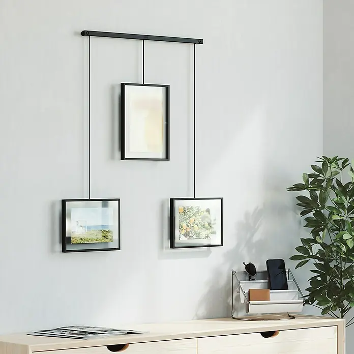 Umbra Bilderrahmen-Set Exhibit - 1 x 13x18 cm, 2 x 10x15 cm, Schwarz, Metall - Ein modernes hängendes Fotorahmen-Set in Schwarz, das an einer Wand befestigt ist und minimalistische Eleganz ausstrahlt.