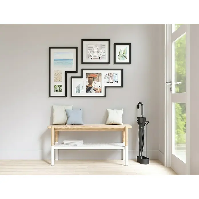 Umbra Juego de marcos - 4 pzs., Negro, Plástico - Interior elegante con banco de madera clara bajo una pared de galería, y un paragüero negro junto a una puerta.