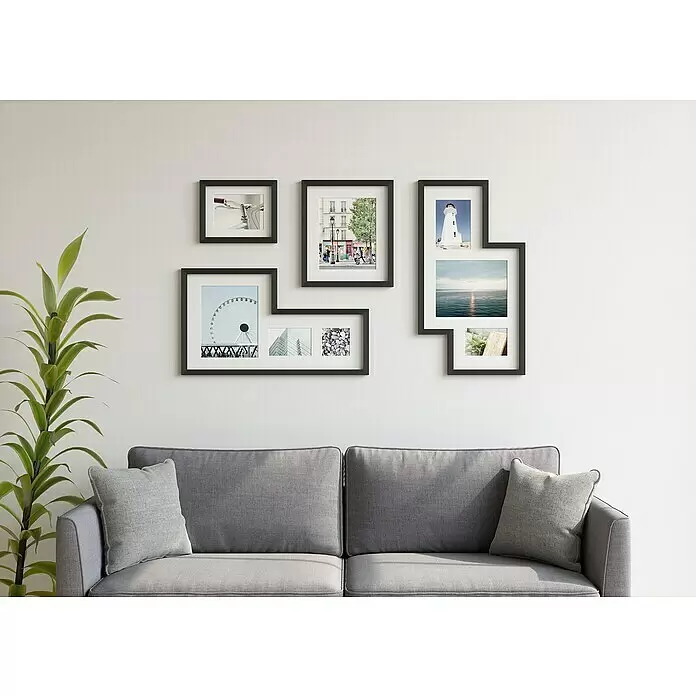 Umbra Juego de marcos - 4 pzs., Negro, Plástico - Sala de estar moderna con un sofá gris, cojines gris claro, una planta verde y una pared de galería con marcos negros.