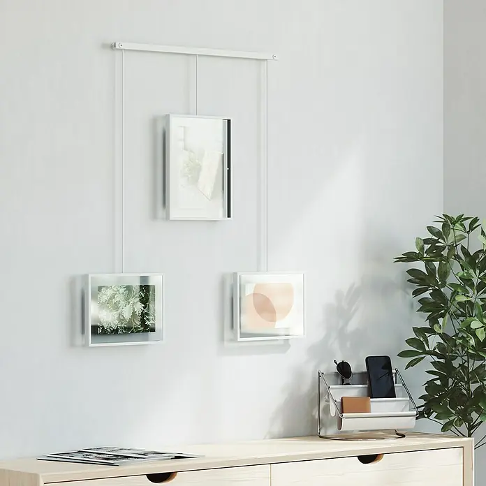 Umbra Bilderrahmen-Set Exhibit - 1 x 13x18 cm, 2 x 10x15 cm, Weiß, Metall - Drei schwebende Fotorahmen in Weiß mit minimalistischen Motiven an einer weißen Wand, Teil eines modernen Dekors.