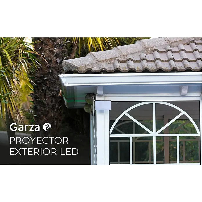 Garza Proyector LED Design - 20 W - Primer plano de un proyector LED de exterior Garza montado en la pared de una casa, con una ventana decorativa al fondo.