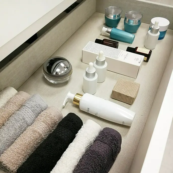Artysan Mueble bajo de lavabo Farbe - L x An x Al: 44,6 x 70 x 64 cm, Roble guadarrama - Una foto de cajón que muestra productos para el cuidado de la piel y toallas enrolladas.