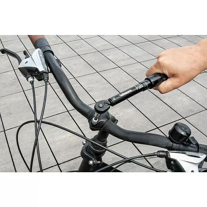Wisent Drehmomentschlüssel - ¼″ Vierkant, 2 Nm - 20 Nm - Hand befestigt mit schwarzem WIESENT Drehmomentschlüssel eine Schraube am Fahrradlenker.